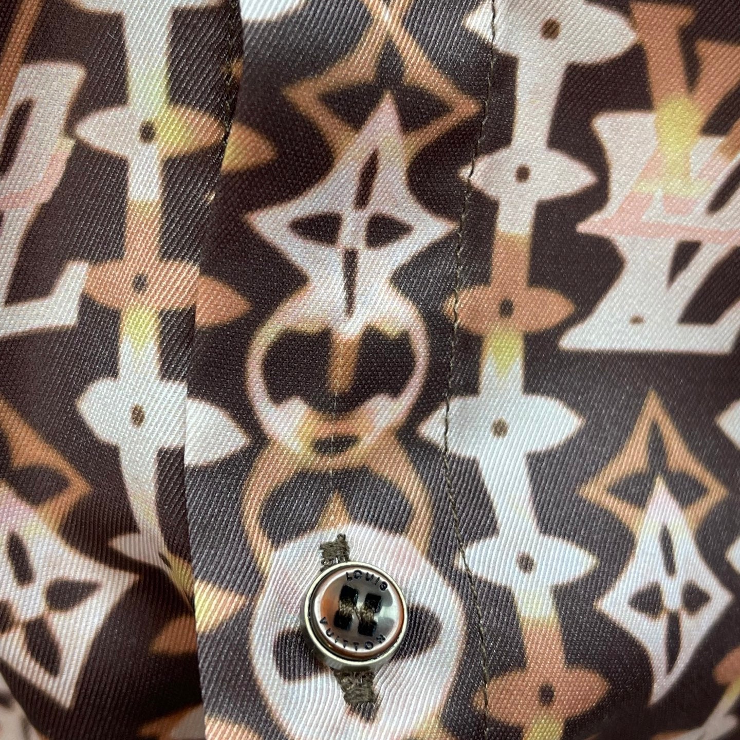 Round button on brown-and-cream monogram button-up shirt, detailed stitching