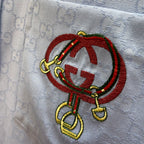 Embroidered crest patch on light blue Gucci shirt, red oval with multicolor accents