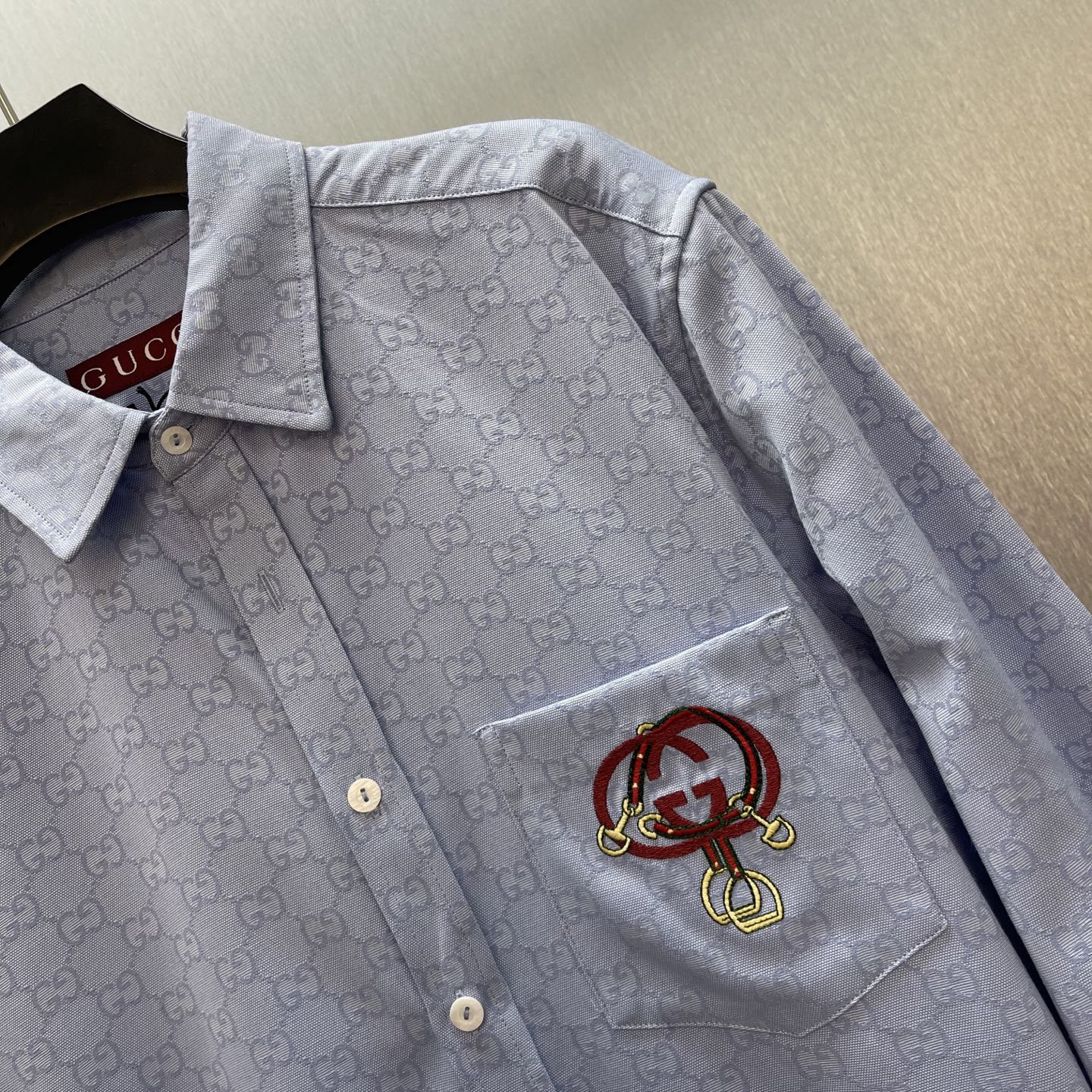 Light blue Gucci long-sleeve shirt with point collar and chest pocket, embroidered crest patch