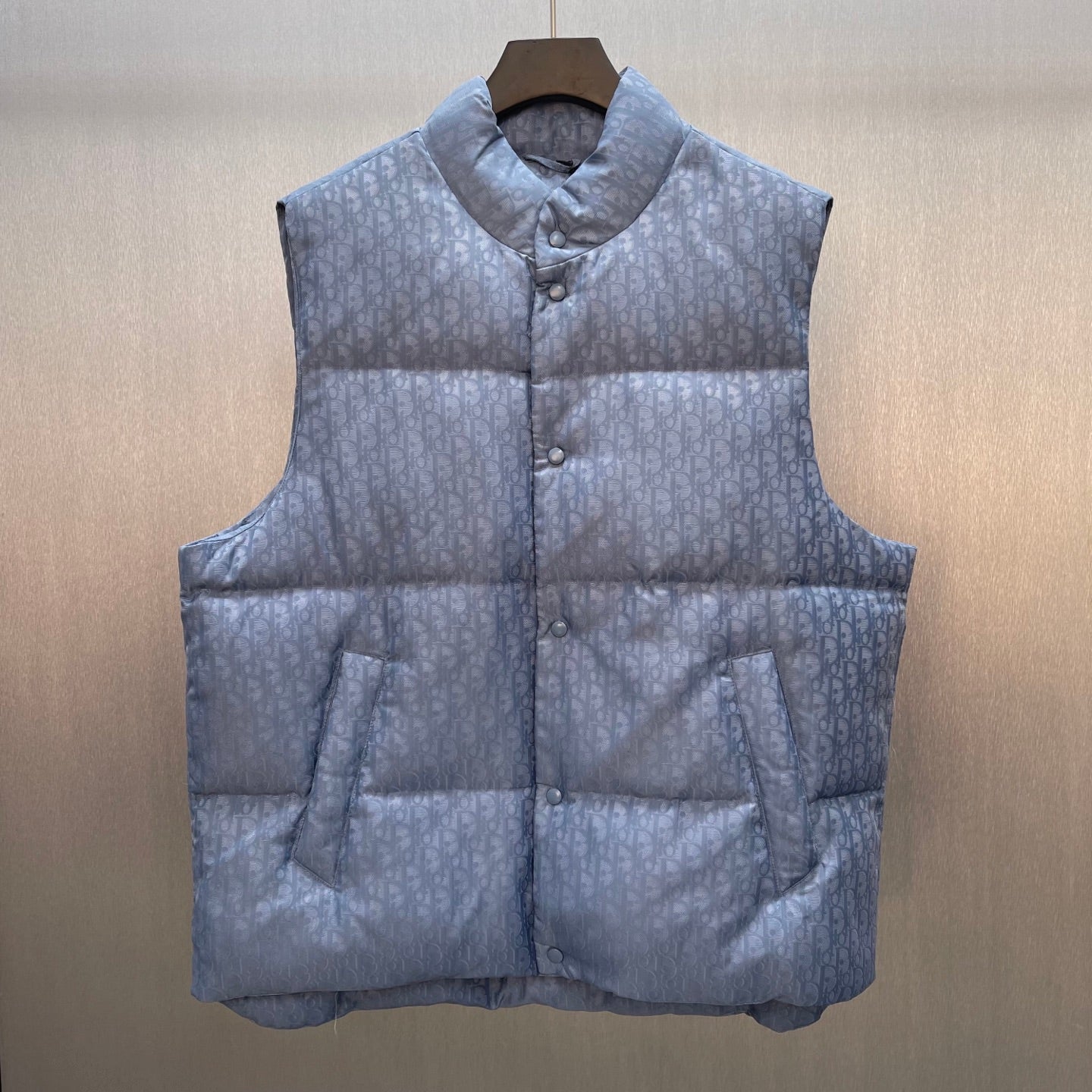 Quilted puffer vest with button front, stand collar, and monogram pattern in light blue