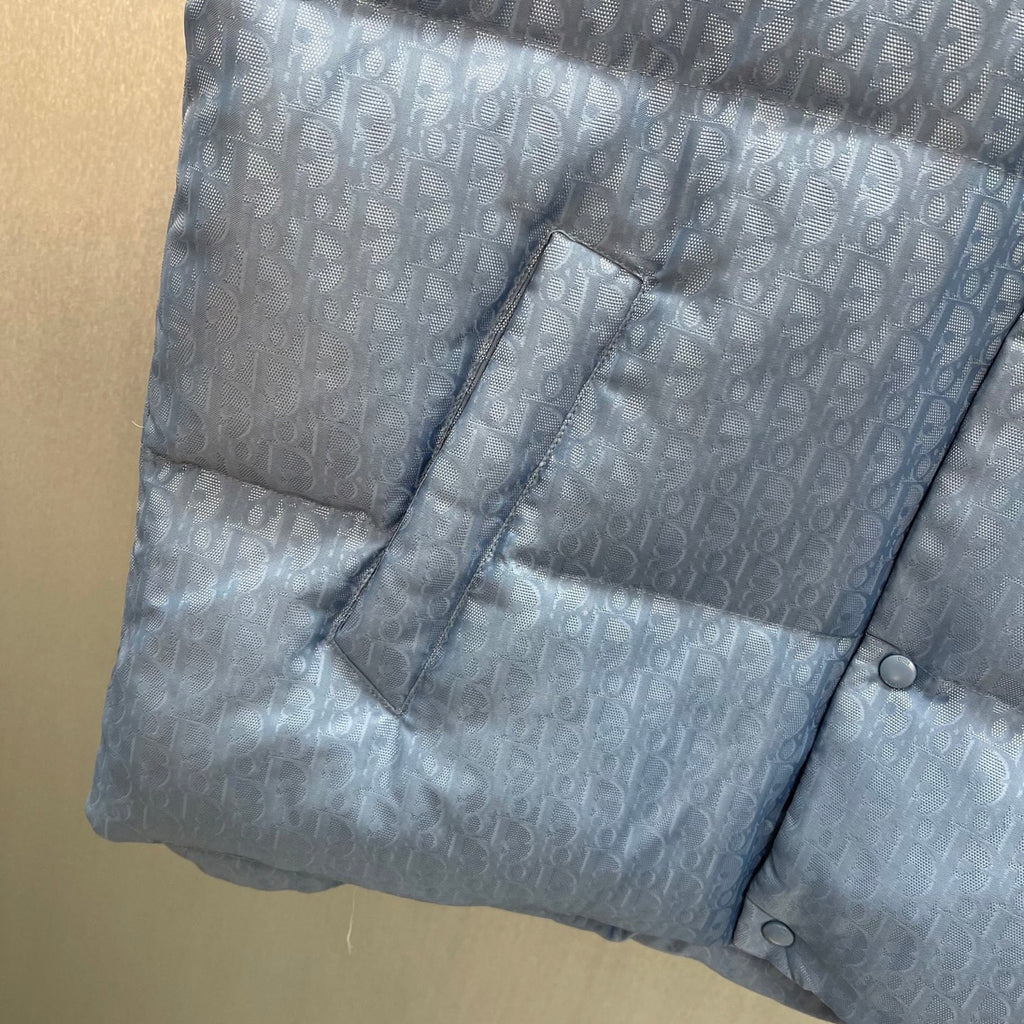 Light blue monogram puffer vest with angled pocket and stitched panel quilting
