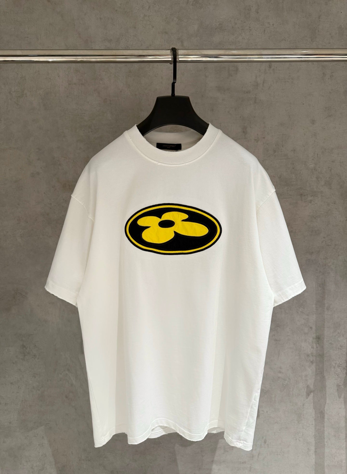 White short-sleeve T-shirt with yellow flower logo on the front