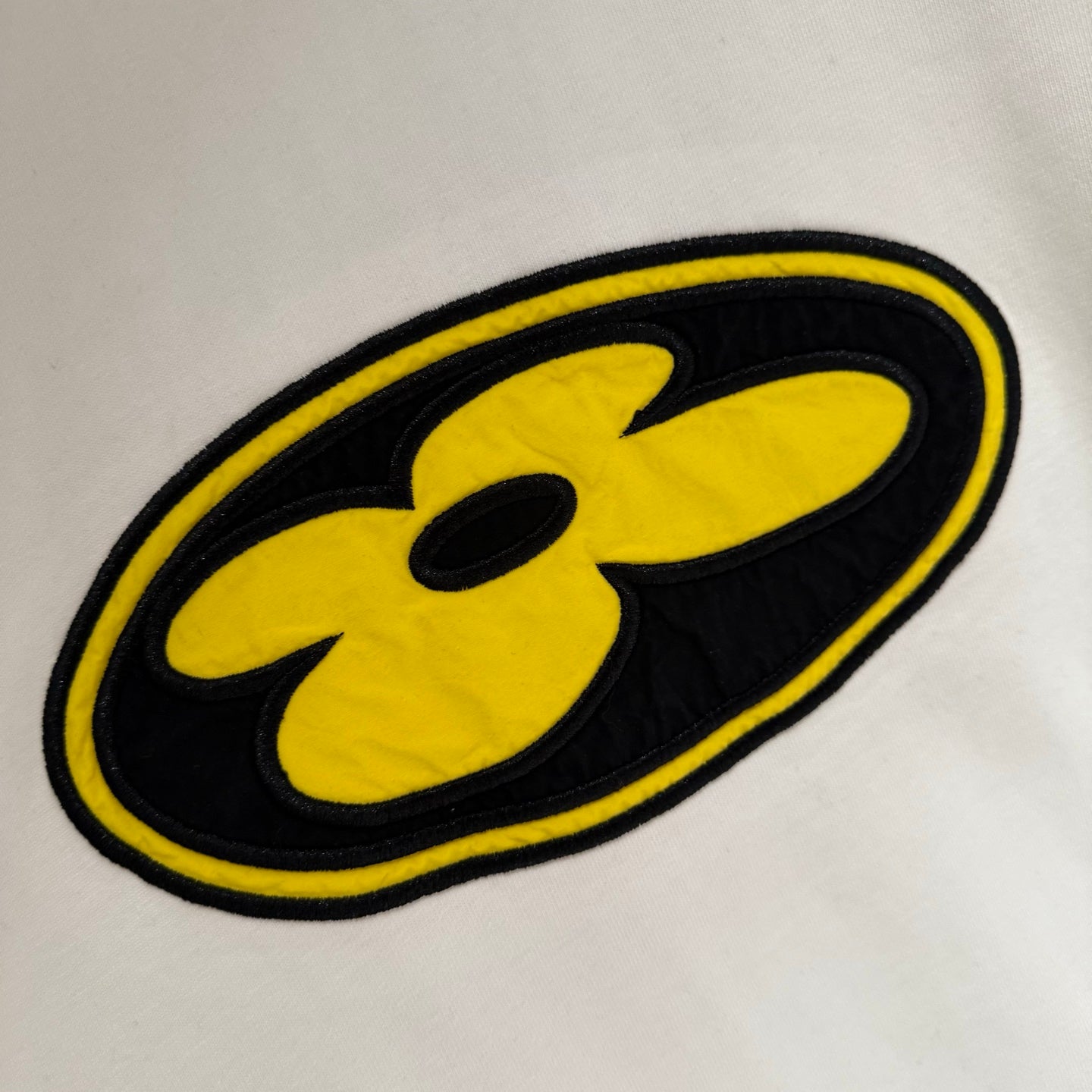 White short-sleeve T-shirt with yellow flower patch logo detail