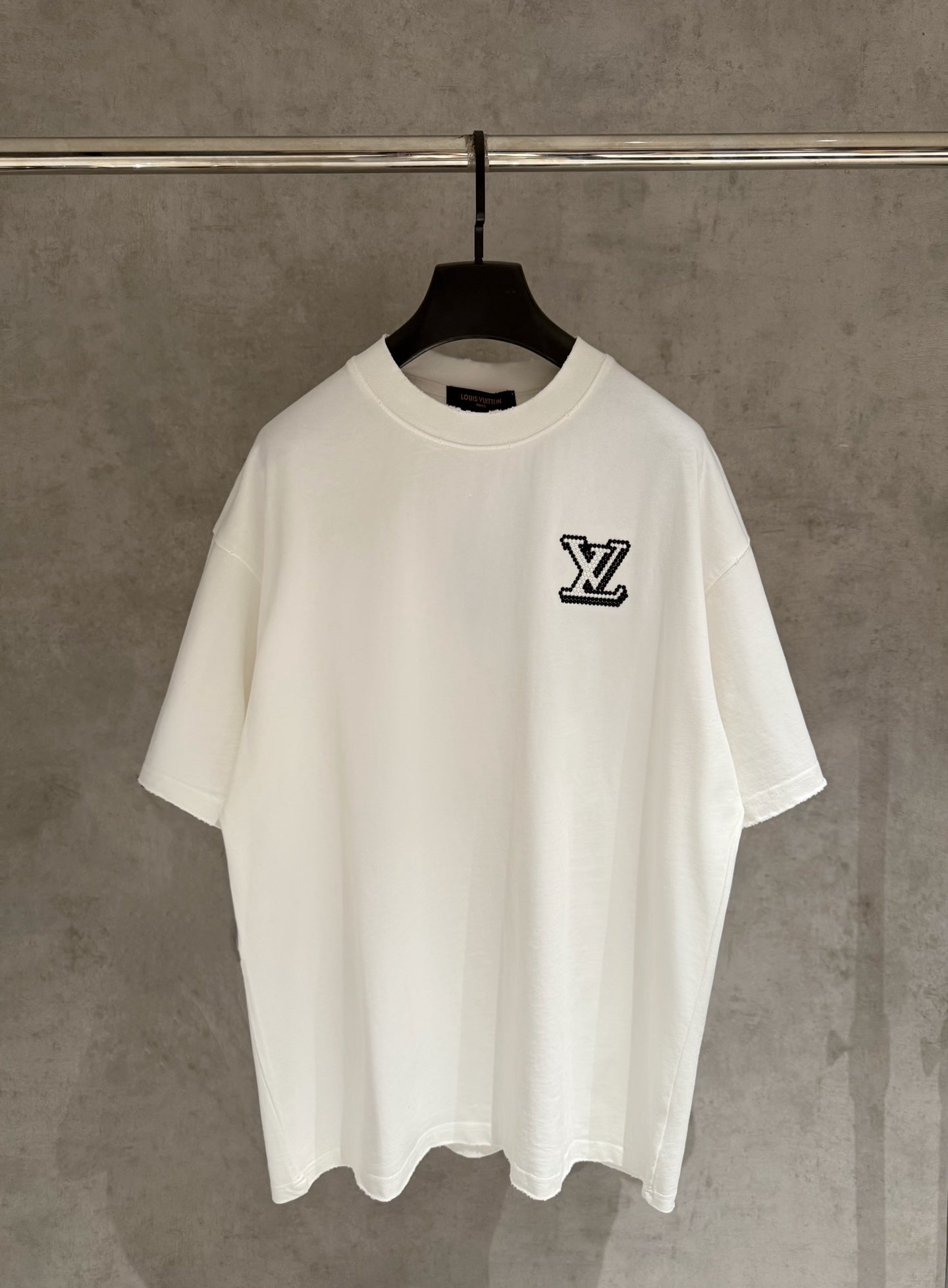 White short-sleeve T-shirt with black LV logo chest on a hanger