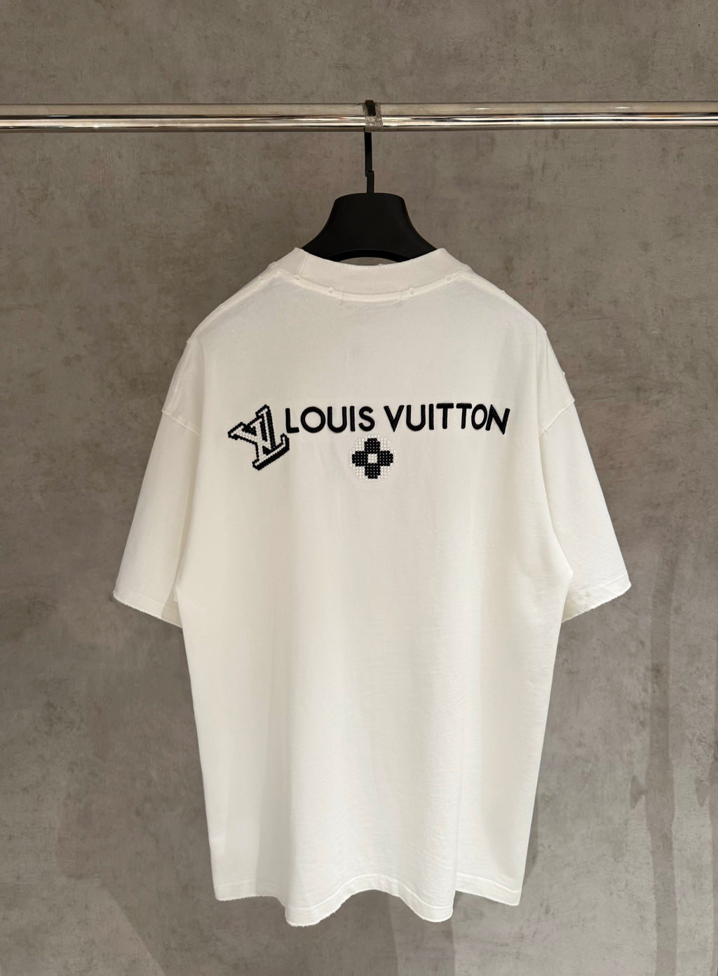 White short-sleeve T-shirt with Louis Vuitton text and black clover emblem