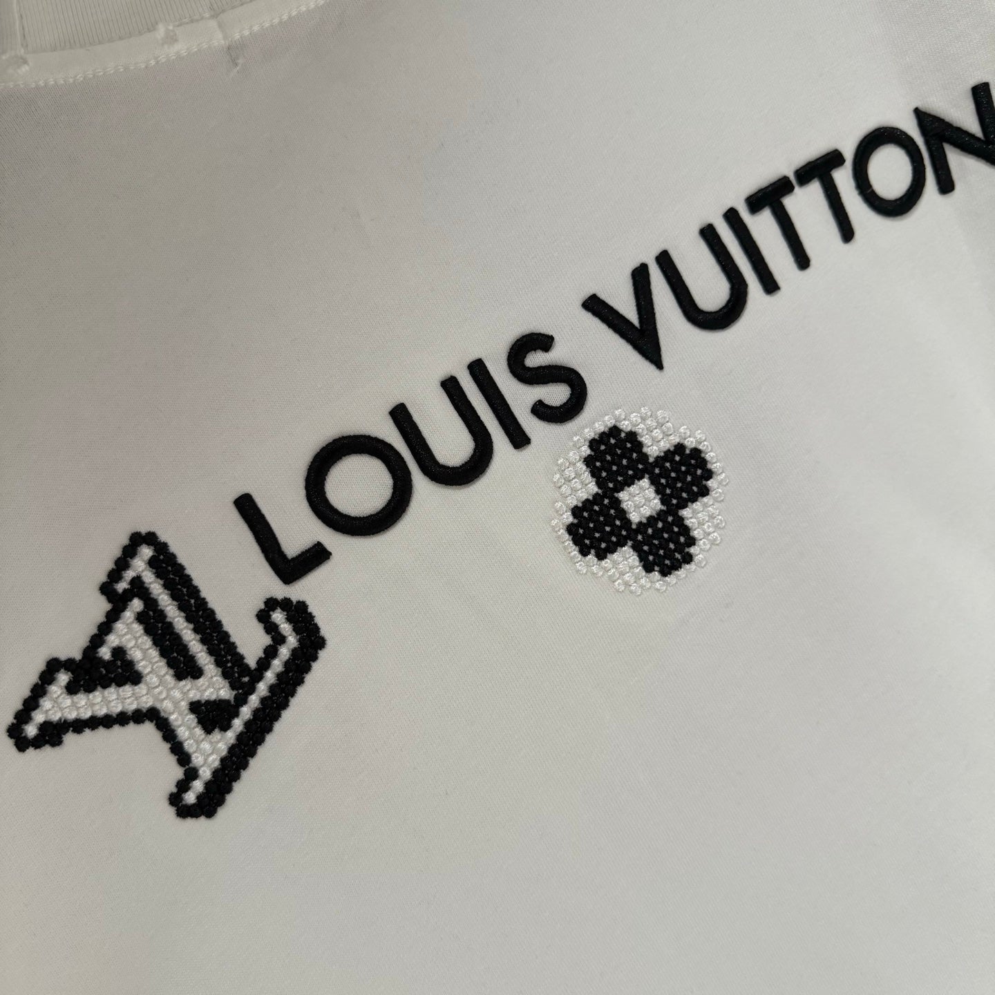 White short-sleeve T-shirt close-up of Louis Vuitton lettering and clover logo