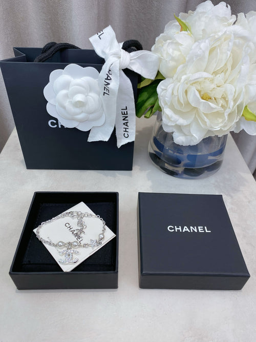 Chanel jewelry box set with a silver charm bracelet on a dark box insert