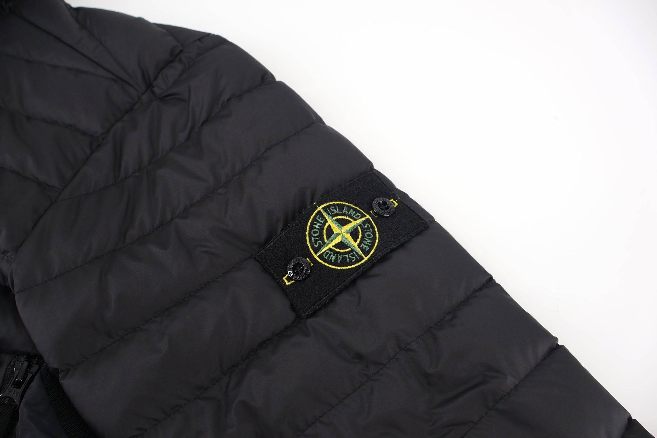 Stone Island logo patch on black puffer jacket sleeve