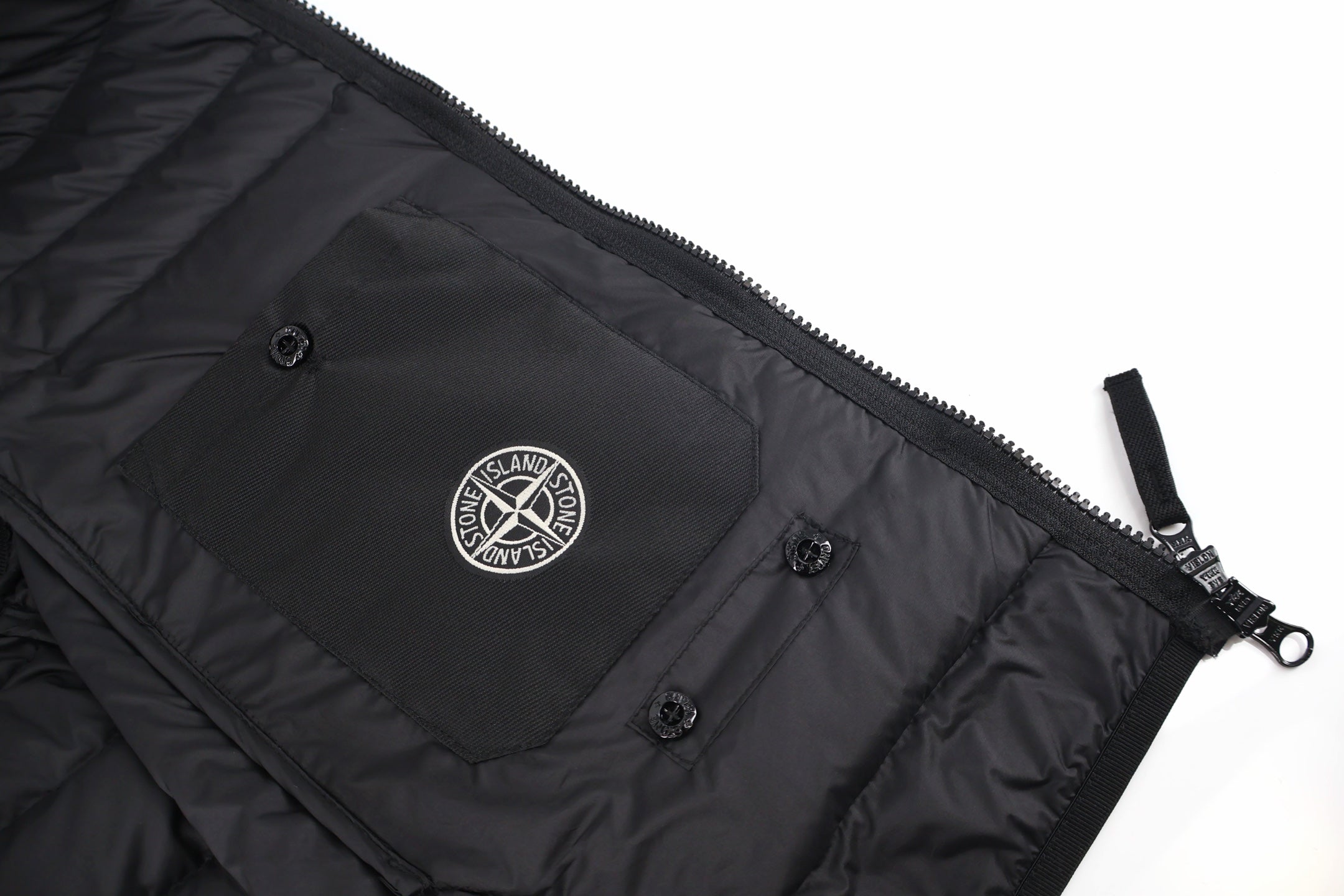 Black puffer jacket inner pocket panel with snaps and Stone Island circular patch