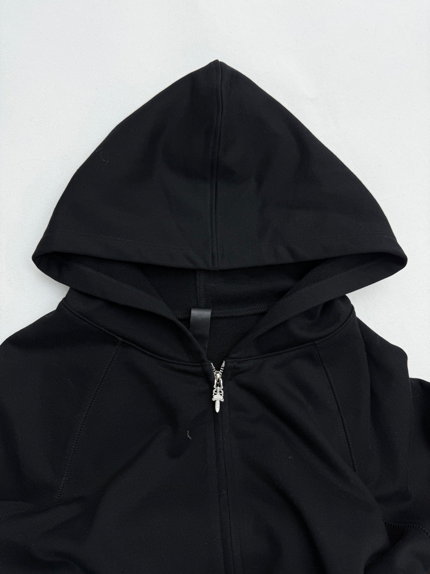Black zip-up hoodie with drawstring hood and silver zipper detail