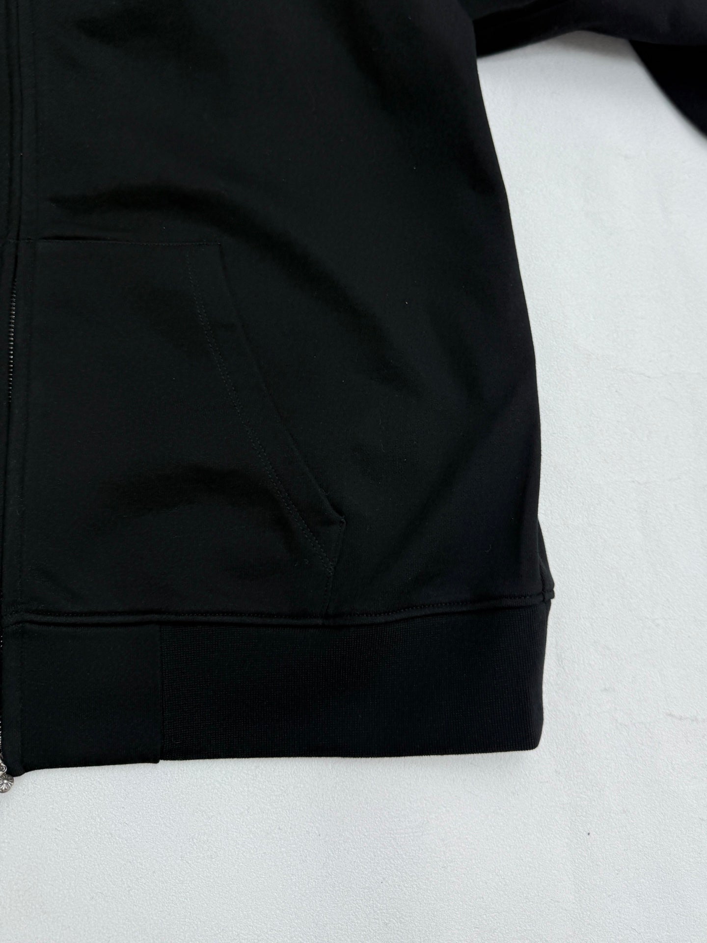 Black hoodie front pocket and hem detail with zipper closure