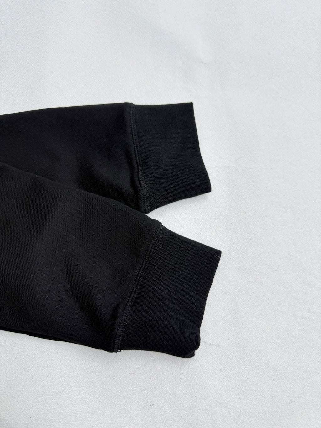 Black hoodie sleeve and cuff detail with visible stitching and seam