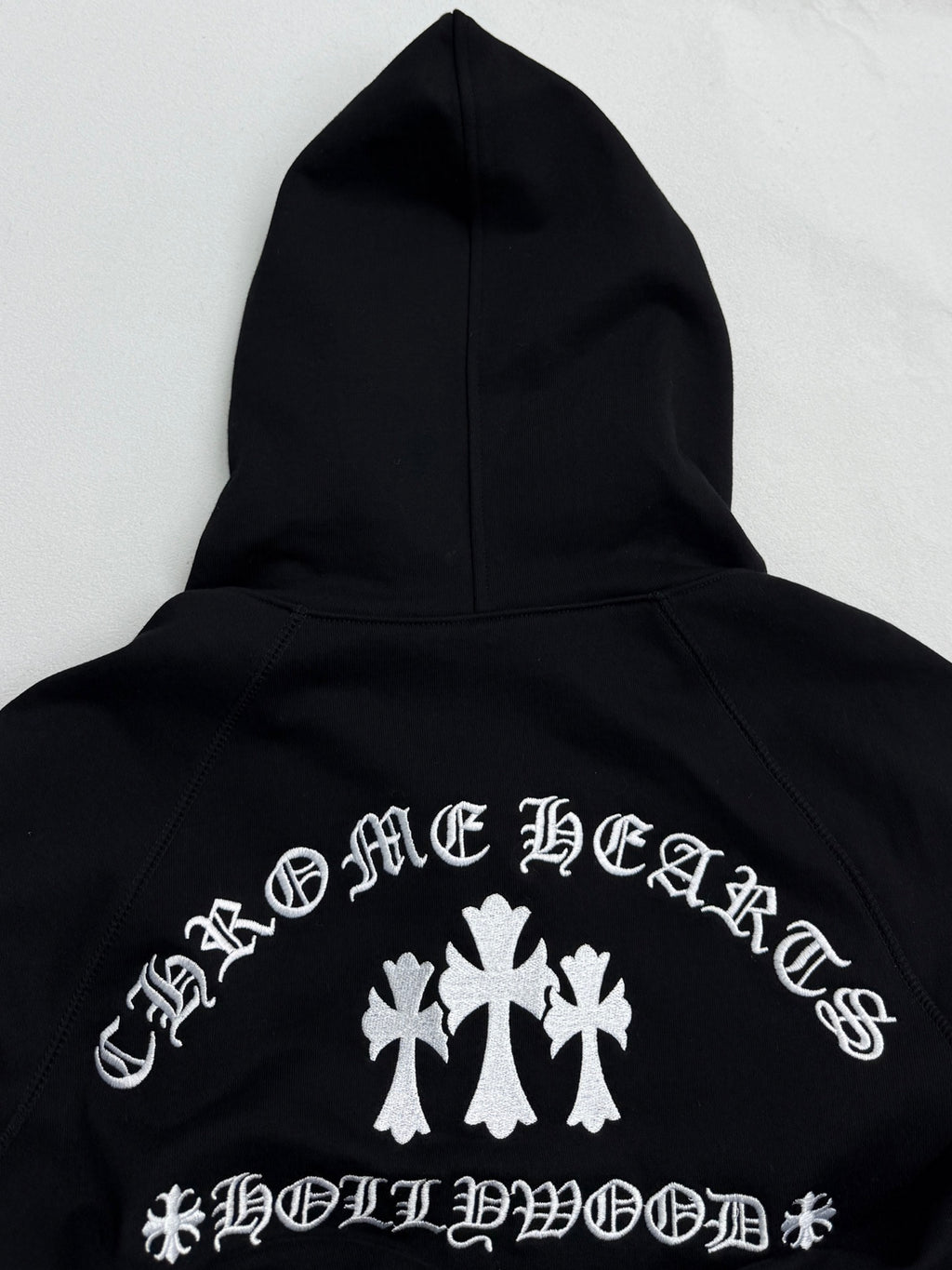 Black hoodie back with white cross-and-leaf style graphic