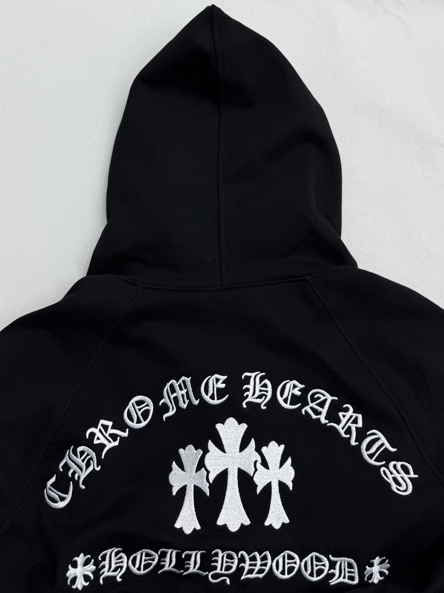 Black hoodie back with white cross-and-leaf style graphic