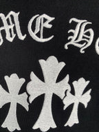 Black hoodie fabric with white cross-flower emblems and decorative lettering