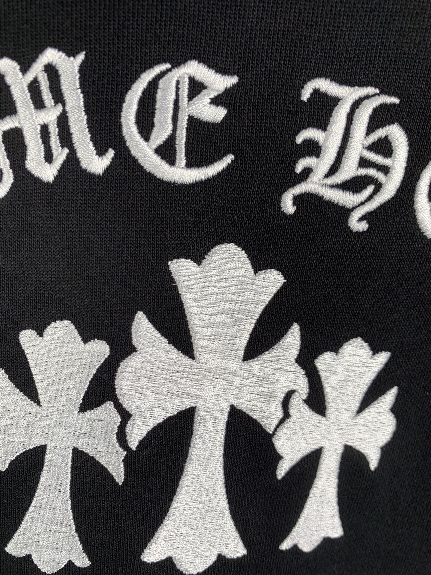 Black hoodie fabric with white cross-flower emblems and decorative lettering