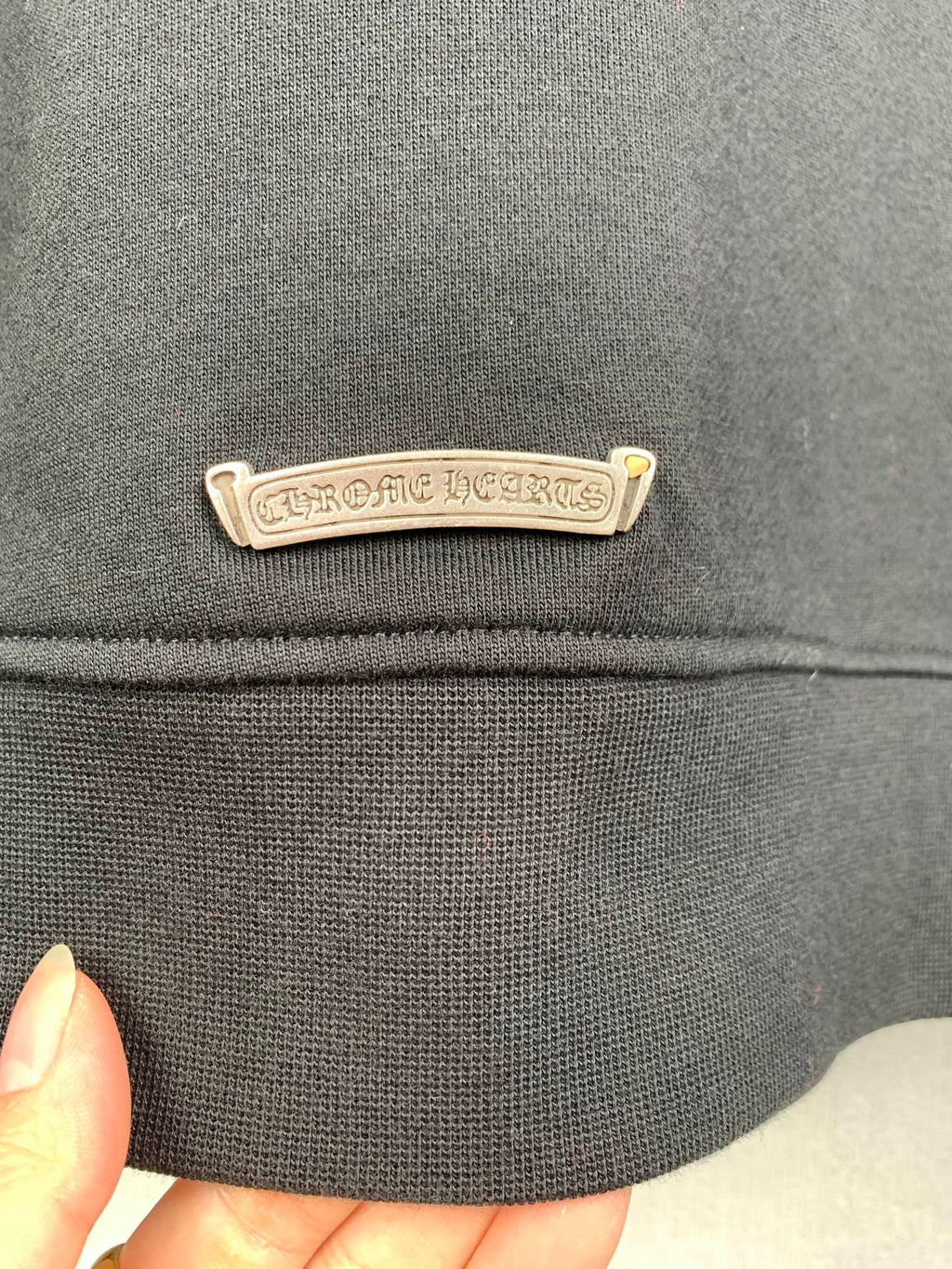 Dark gray hoodie chest logo label in chrome-tone metal