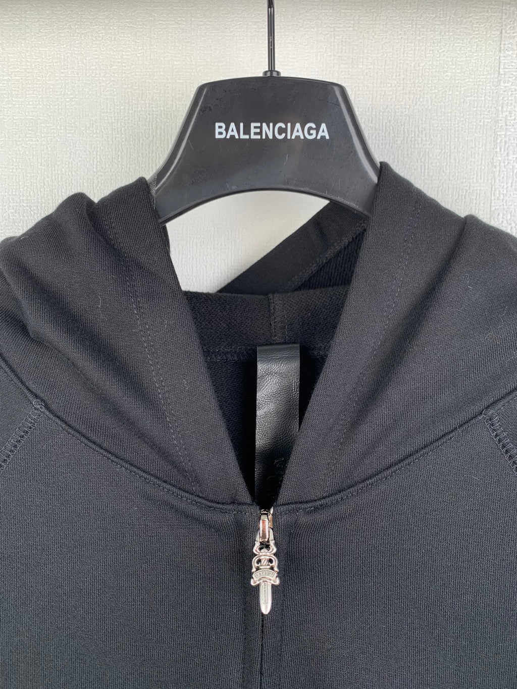 Black zip-up hoodie close-up with metal zipper pull and hood lining