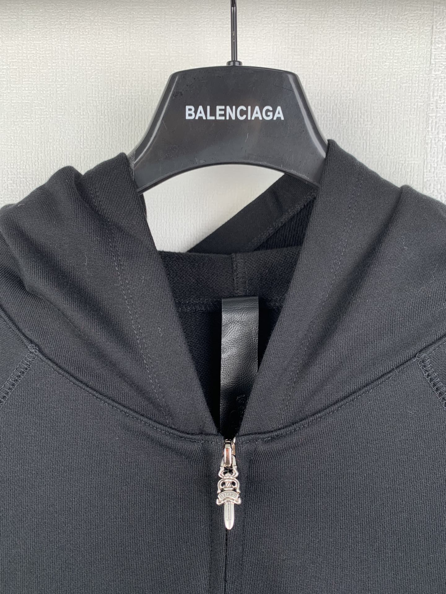 Black zip-up hoodie close-up with metal zipper pull and hood lining