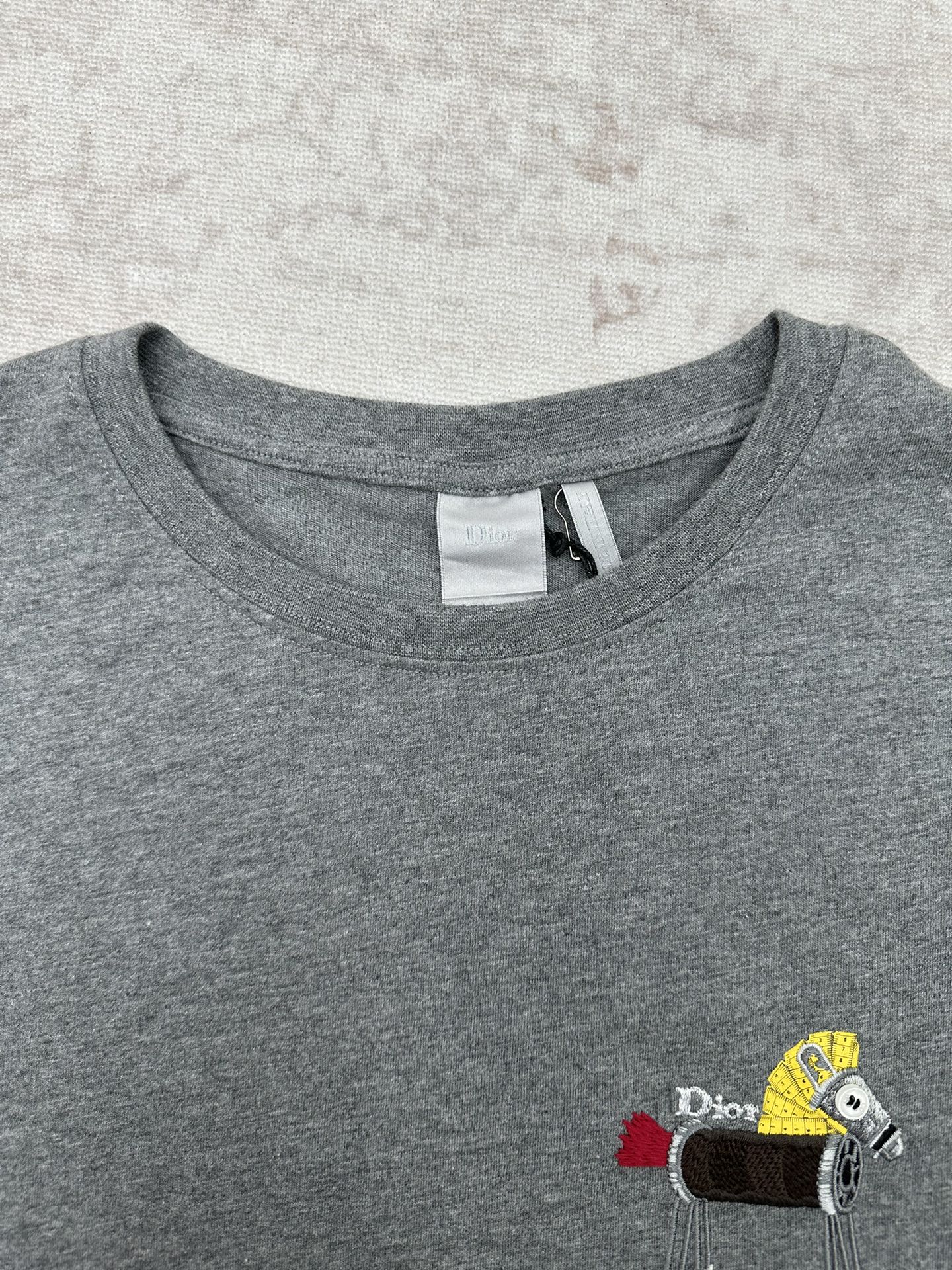 Grey T-shirt neckline with brand tag and embroidered front patch graphic