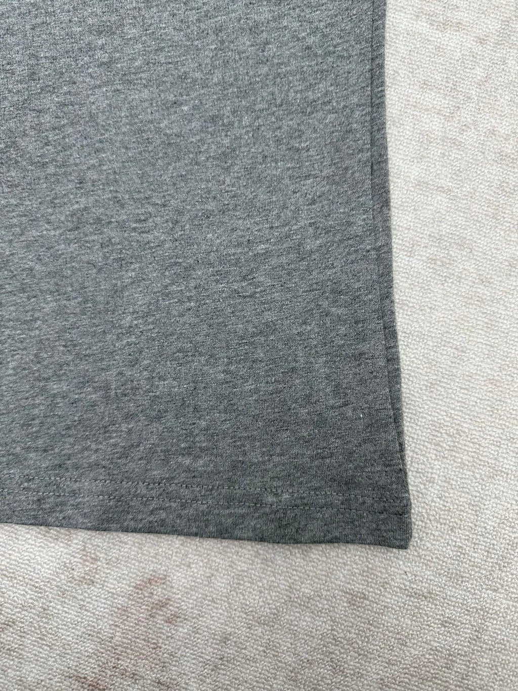 Grey short-sleeve T-shirt hem close-up, straight side seam