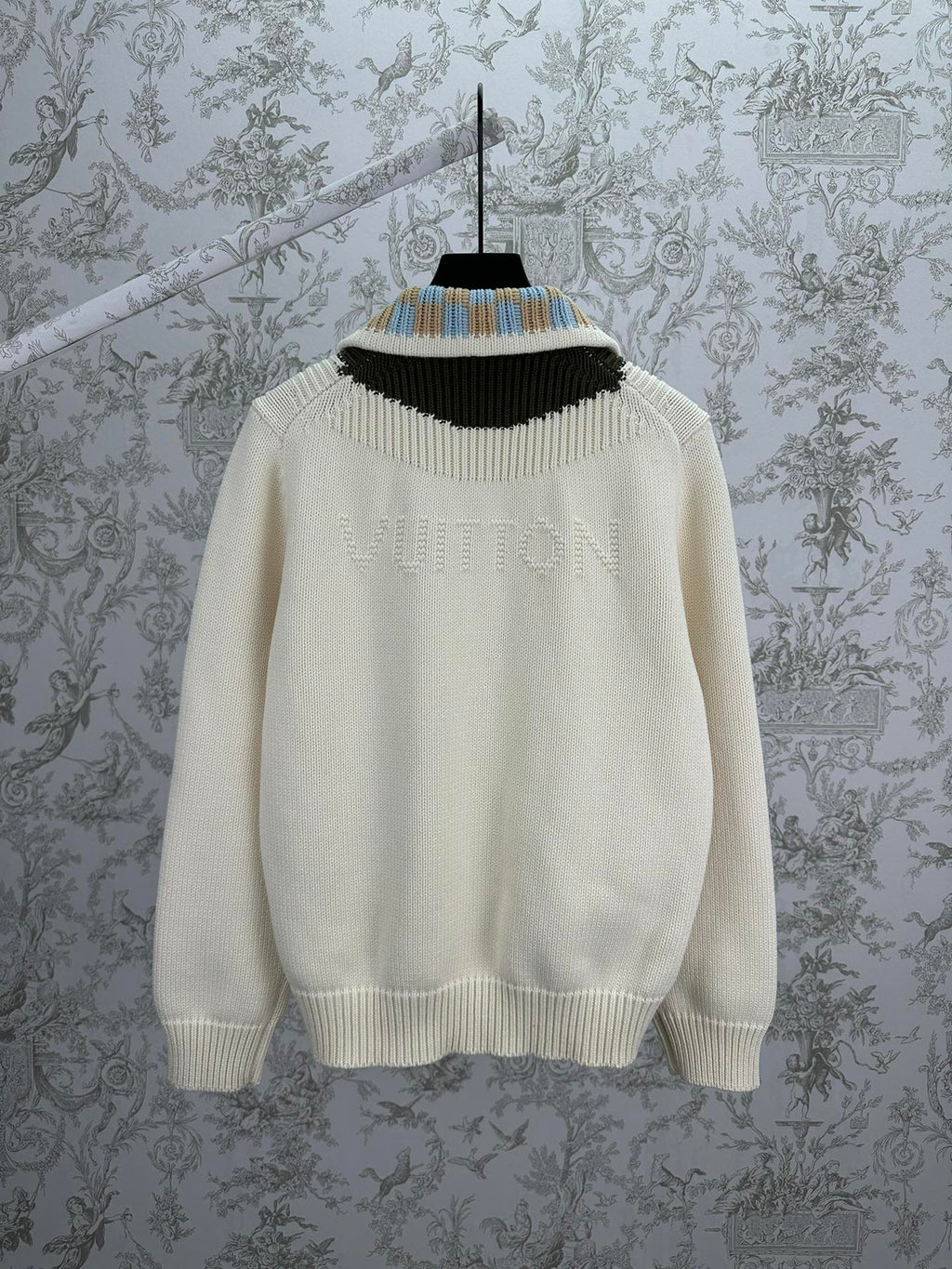 Cream knit cardigan neckline with black, blue, and tan striped rib trim