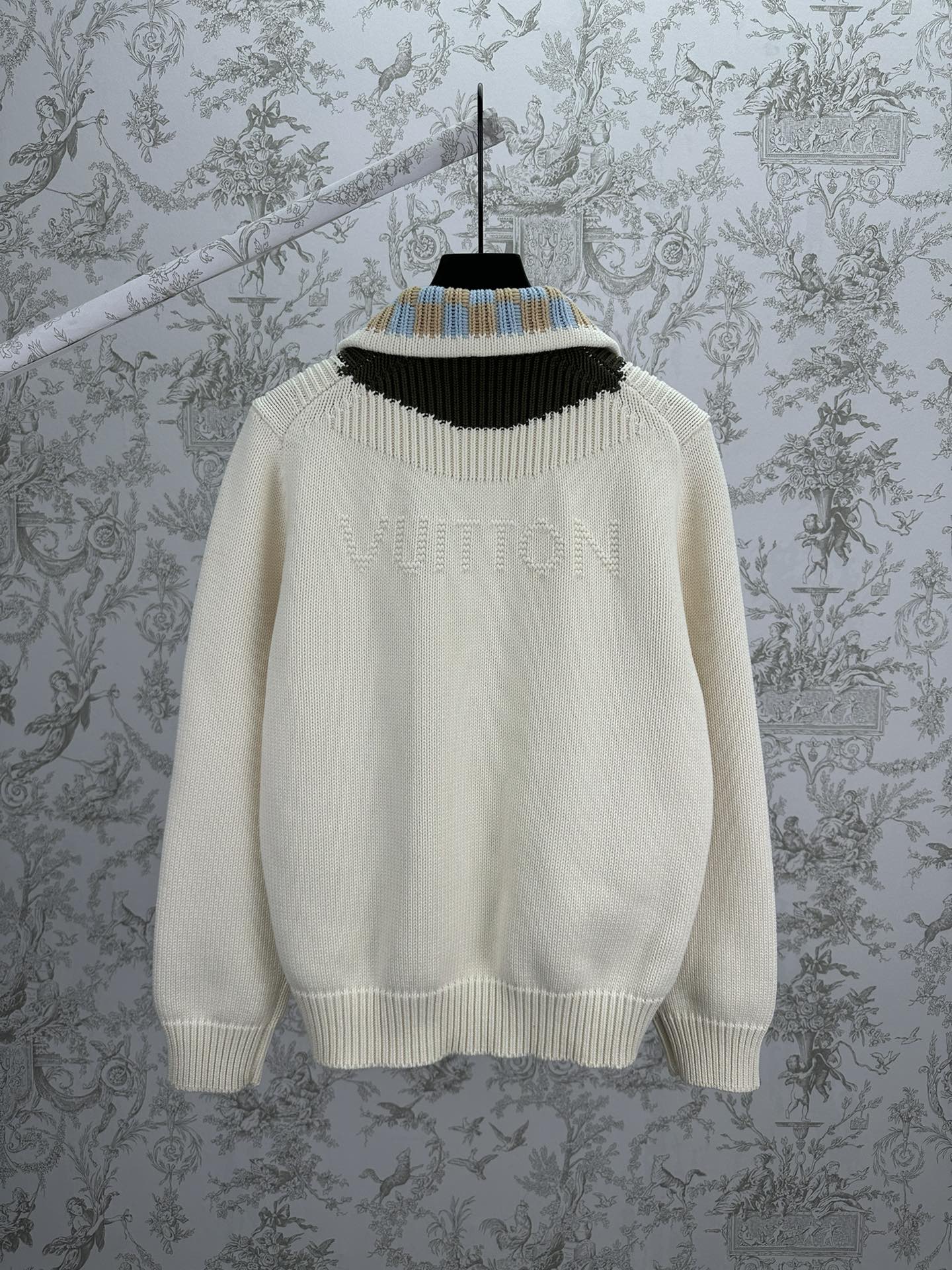 Cream knit cardigan neckline with black, blue, and tan striped rib trim