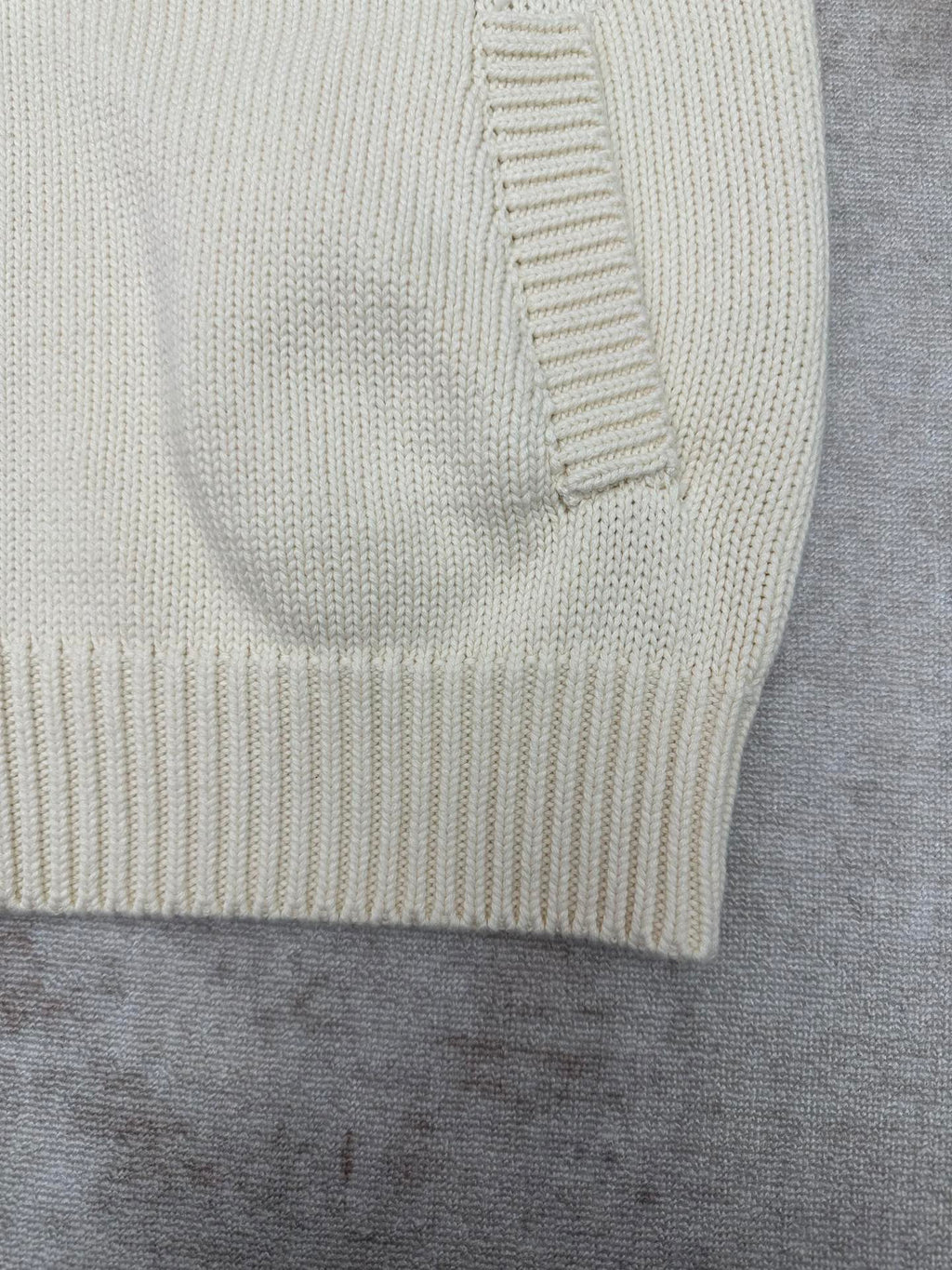 Cream knit cardigan sleeve cuff with ribbed trim close-up