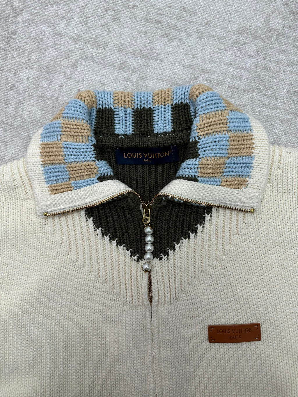 Cream cardigan collar with blue-and-tan striped trim and black V-shaped panel