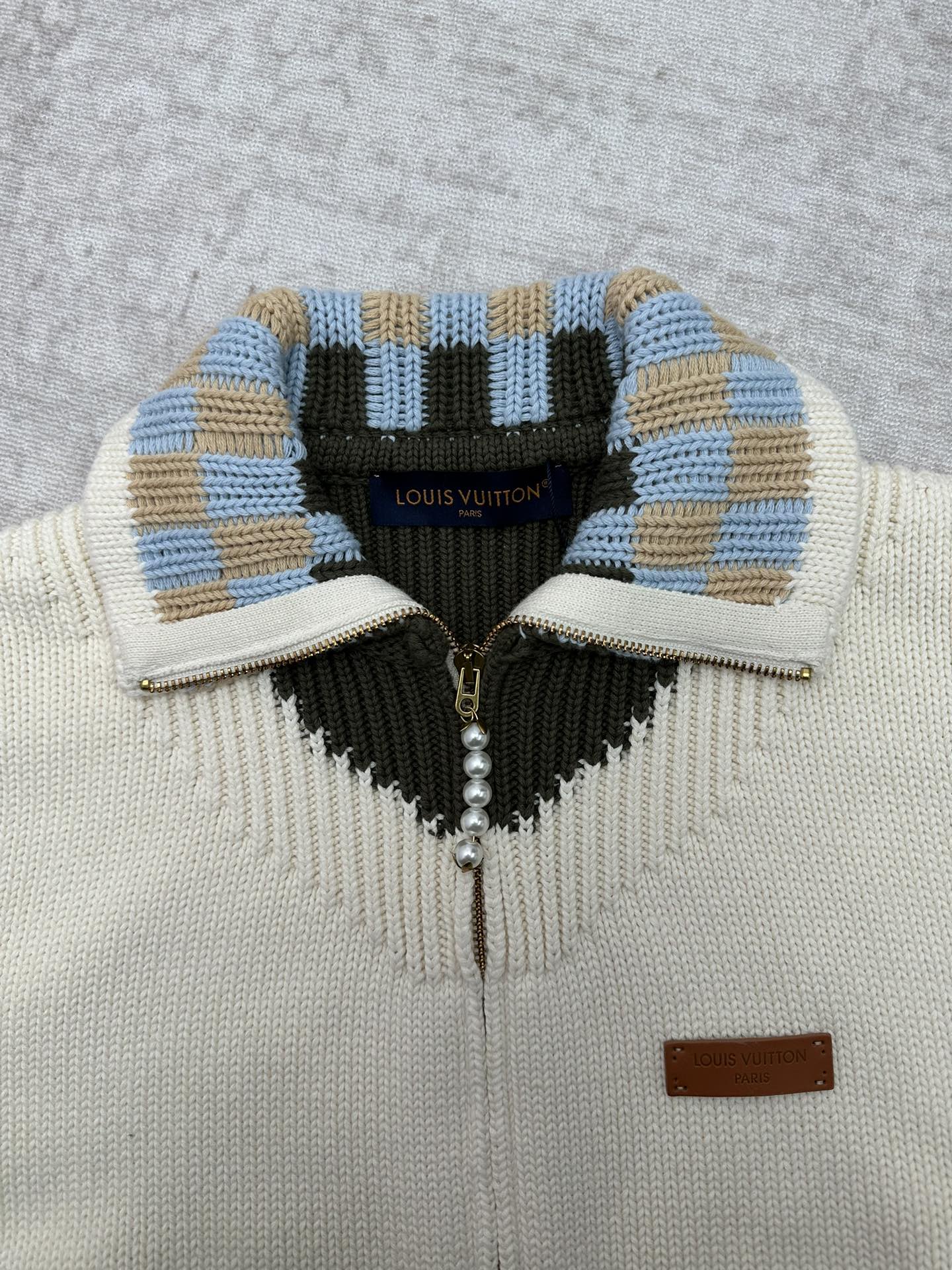 Cream cardigan collar with blue-and-tan striped trim and black V-shaped panel