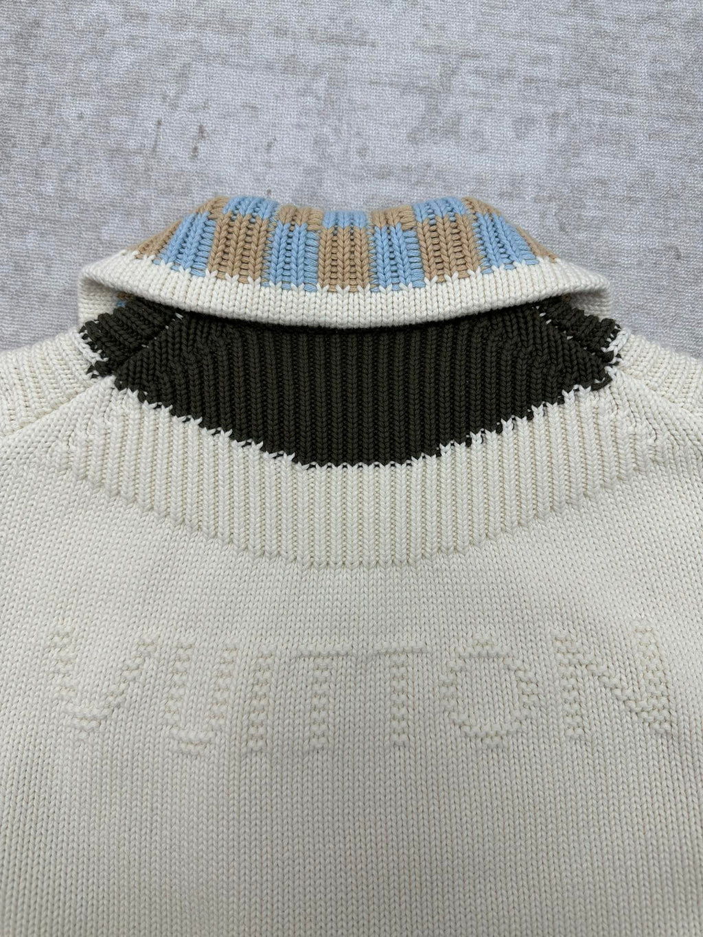 Cream knit cardigan collar with blue-and-tan check stripe and black band
