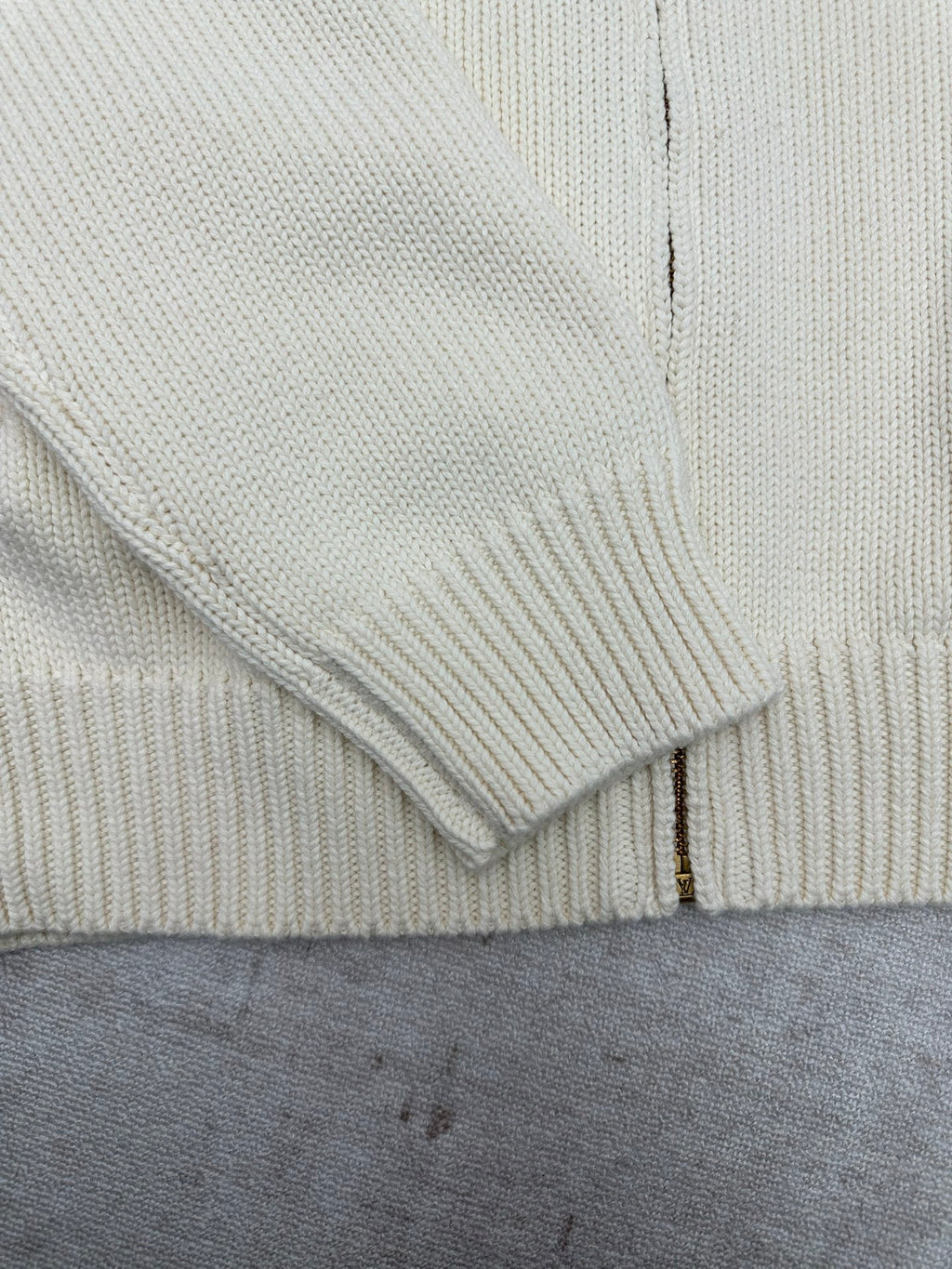 Cream knit cardigan cuff and zipper placket close-up