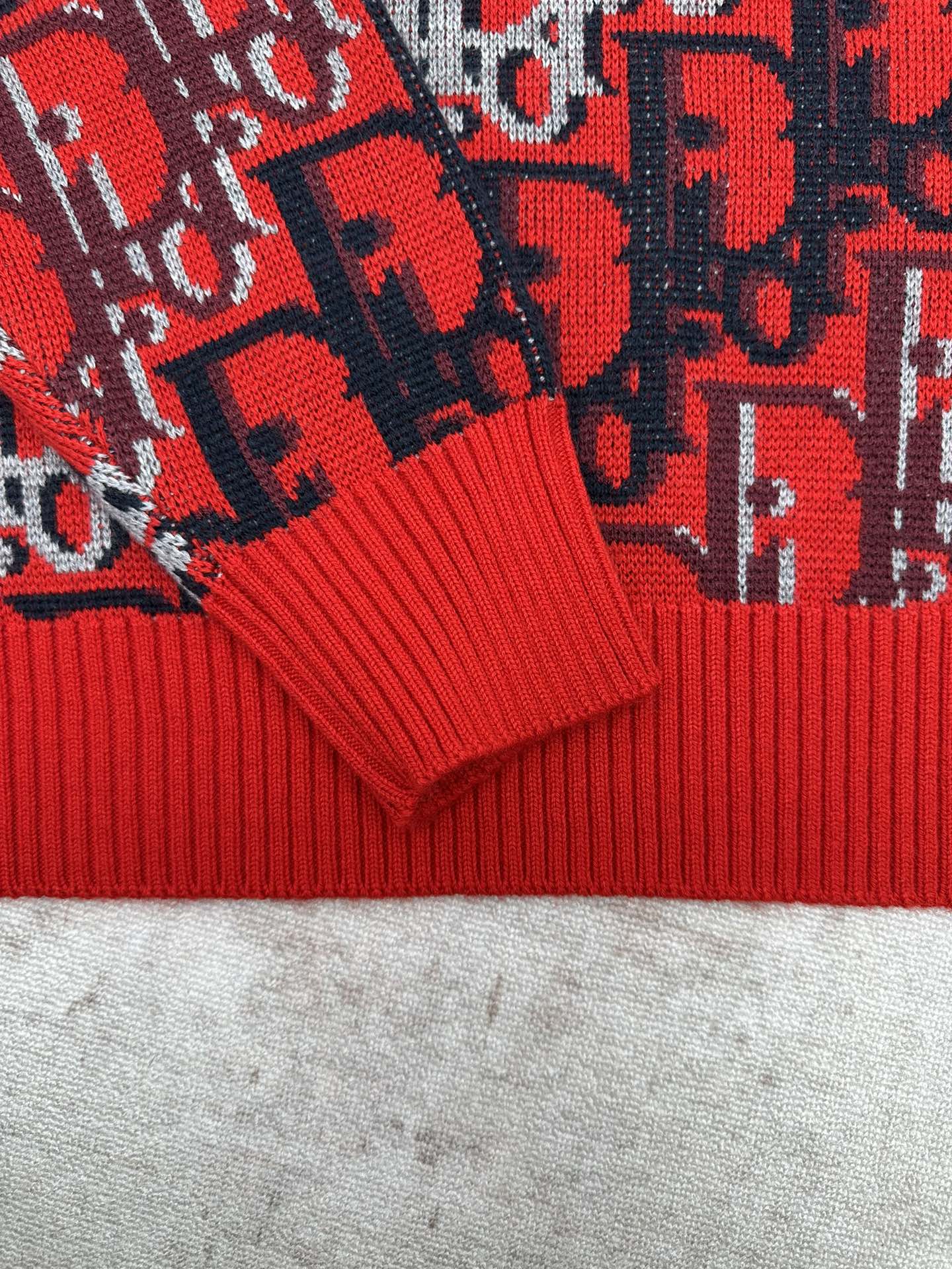 Dior knit sweater cuffs with ribbed red hem and dark blue patterned fabric panels