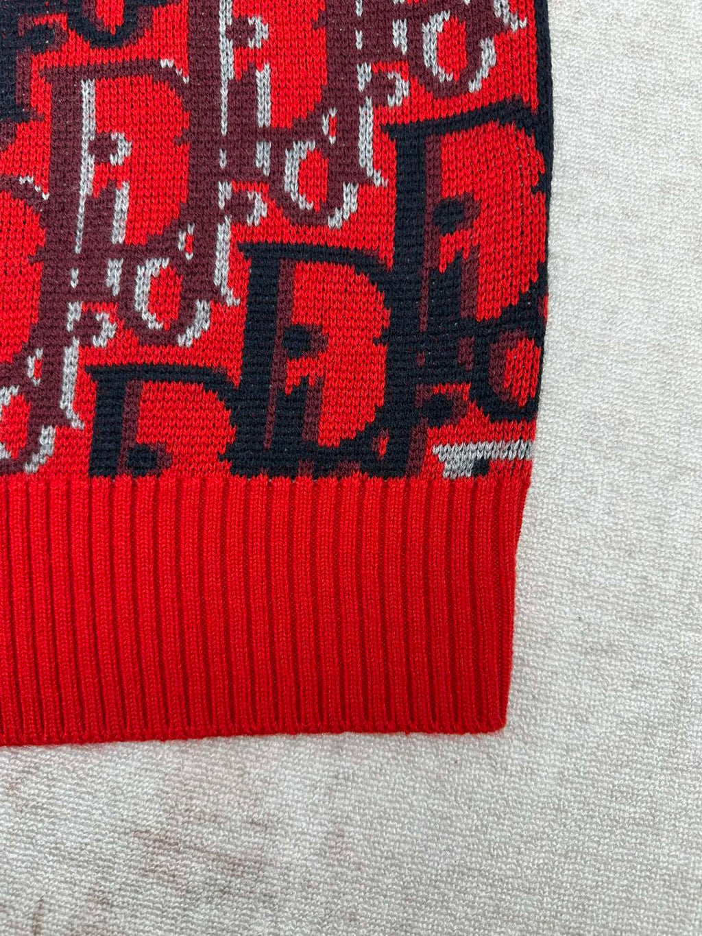 Dior knit sweater lower hem with red ribbed trim and dark blue logo pattern