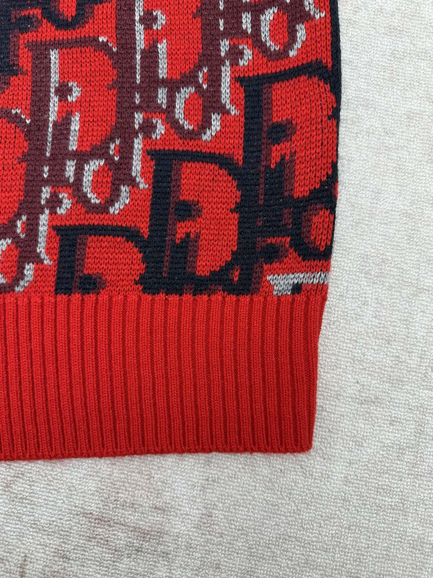 Dior knit sweater lower hem with red ribbed trim and dark blue logo pattern