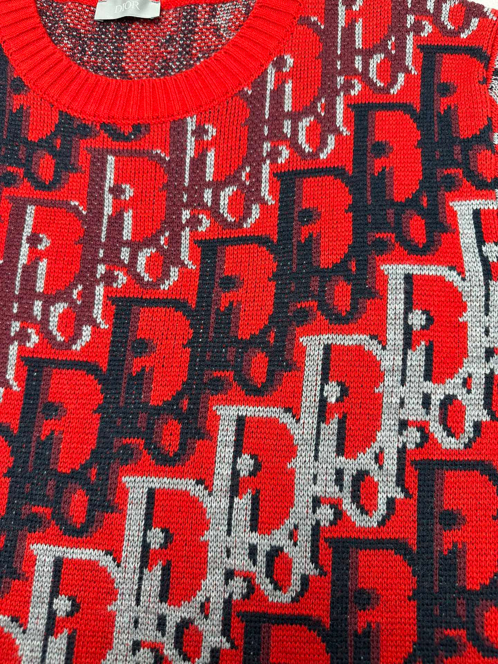 Dior knit sweater with red logo motif over dark blue knit, textured fabric surface