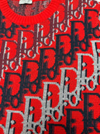 Dior knit sweater with red logo motif over dark blue knit, textured fabric surface