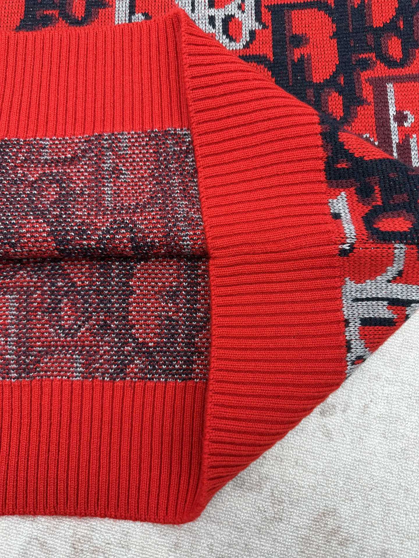 Dior knit sweater sleeve with red ribbed cuff and dark blue patterned knit
