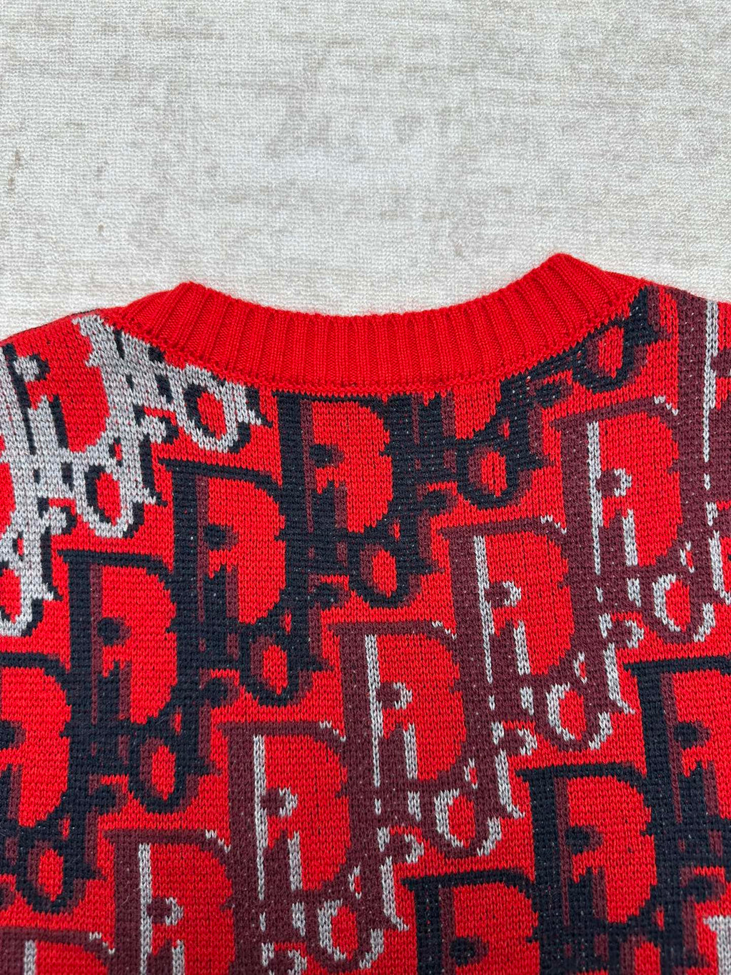 Dior knit sweater upper body with repeating red logo pattern on dark blue