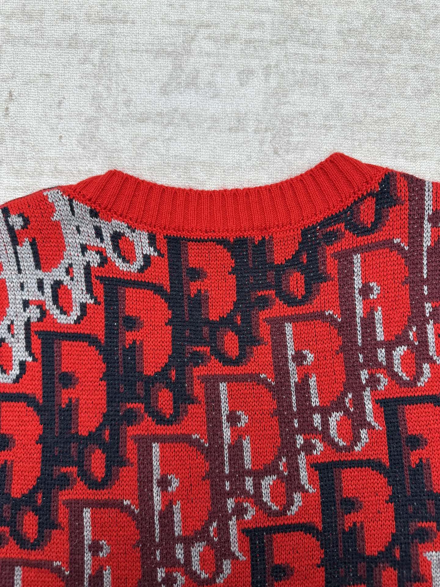 Dior knit sweater upper body with repeating red logo pattern on dark blue