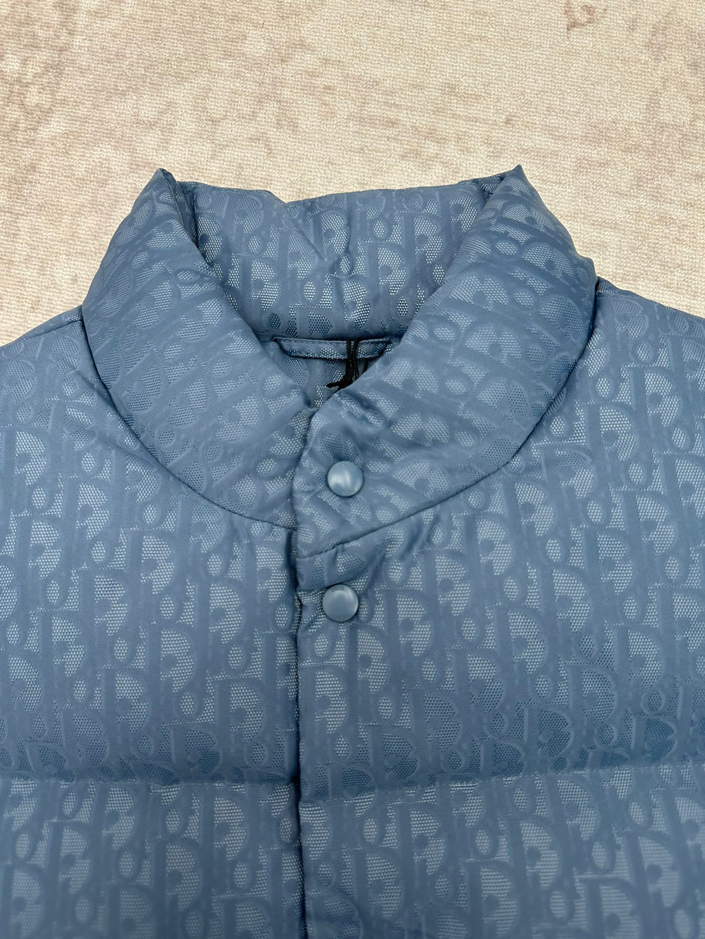 Blue Dior monogram puffer vest close-up of stand collar and two snap buttons.