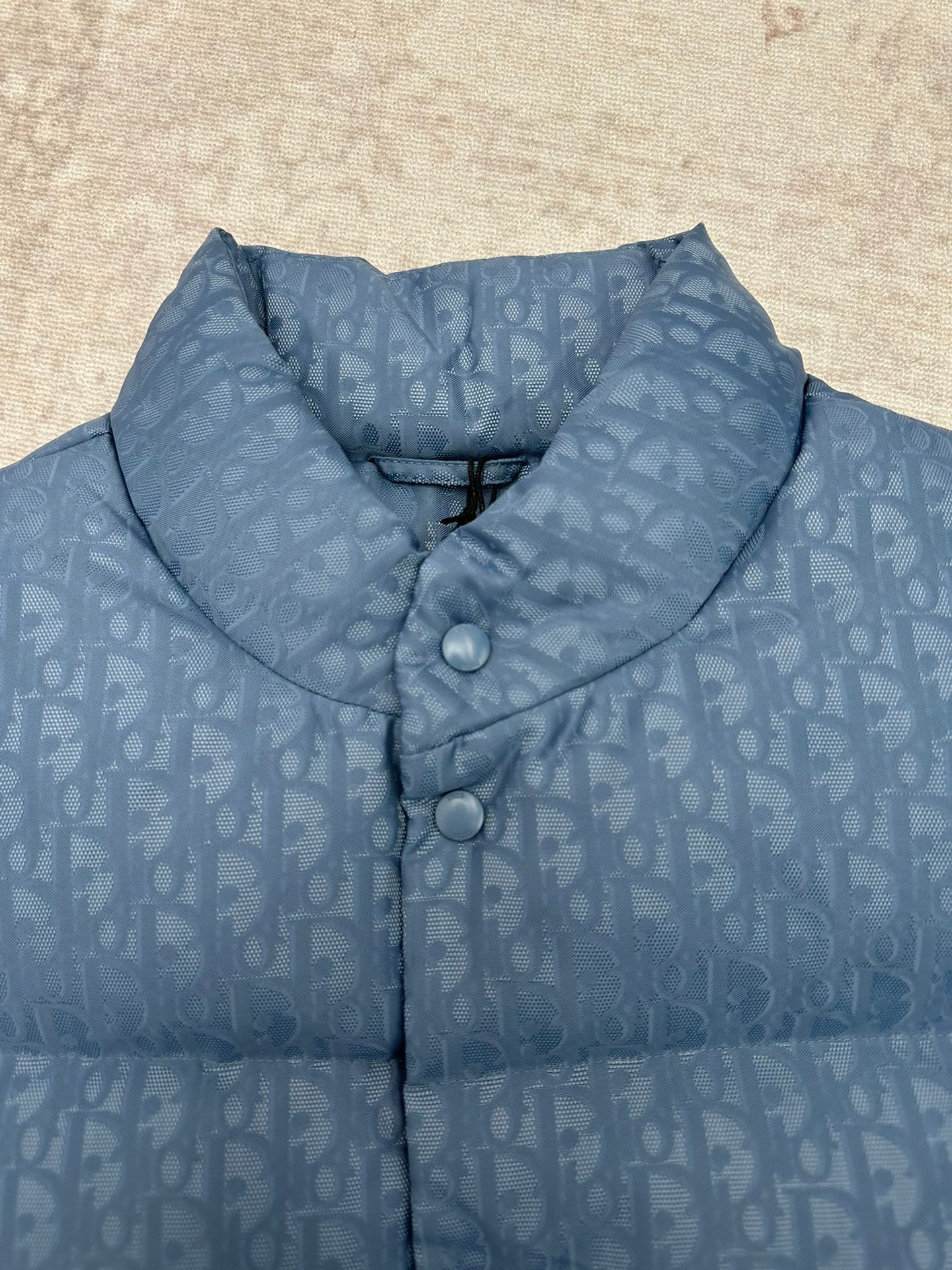 Blue Dior monogram puffer vest close-up of stand collar and two snap buttons.