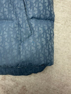 Blue Dior monogram puffer vest bottom hem detail with stitched quilting and curved edge.