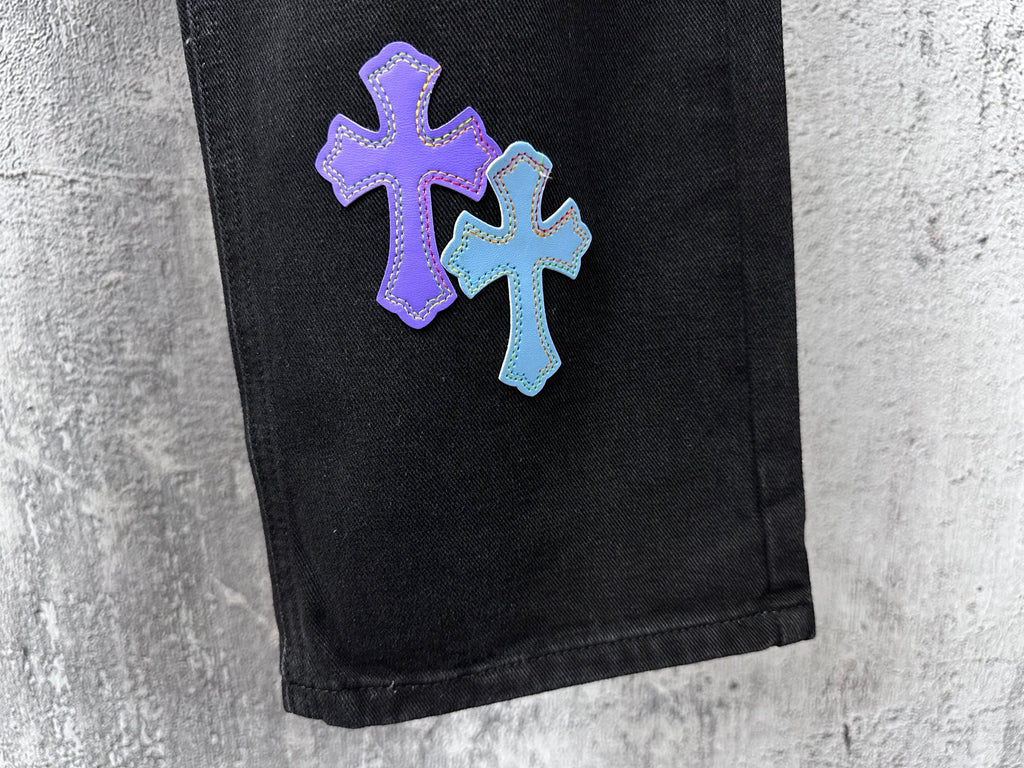 Black denim pants with purple and light-blue cross patch near hem