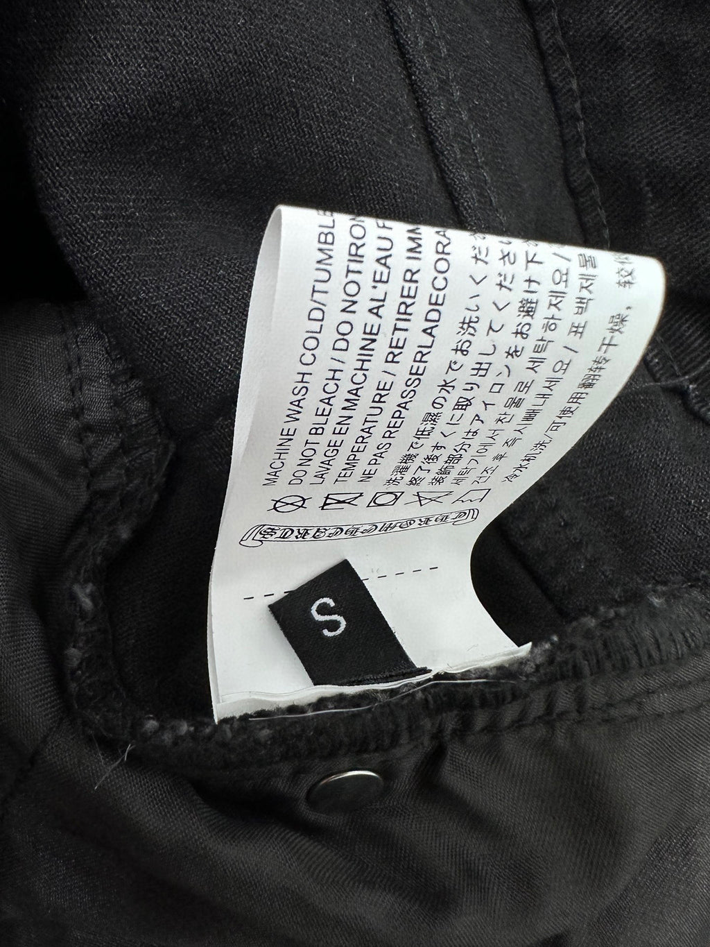 Black denim pants with size label inside waistband and care text tag