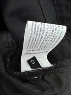 Black denim pants with size label inside waistband and care text tag