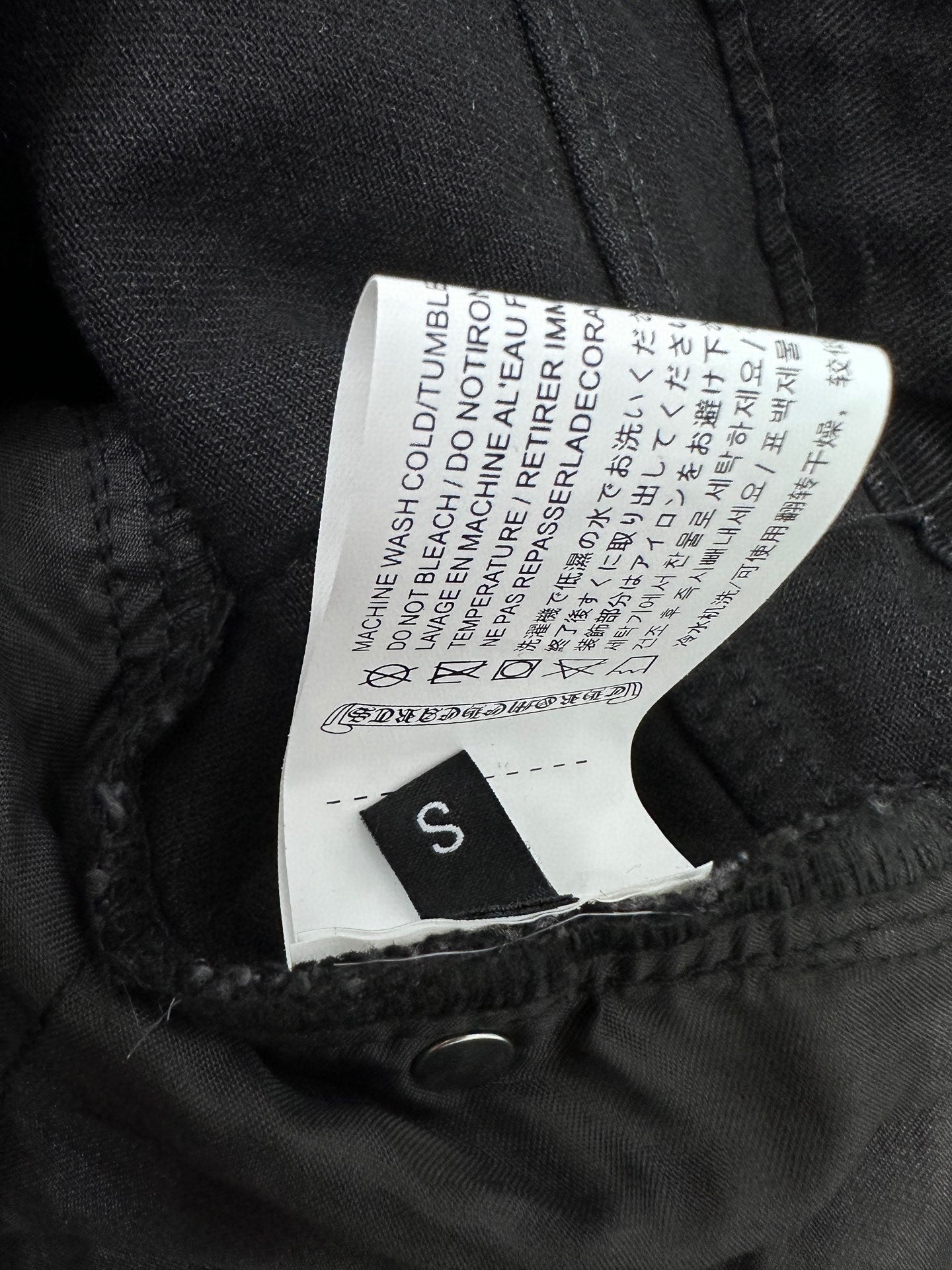 Black denim pants with size label inside waistband and care text tag