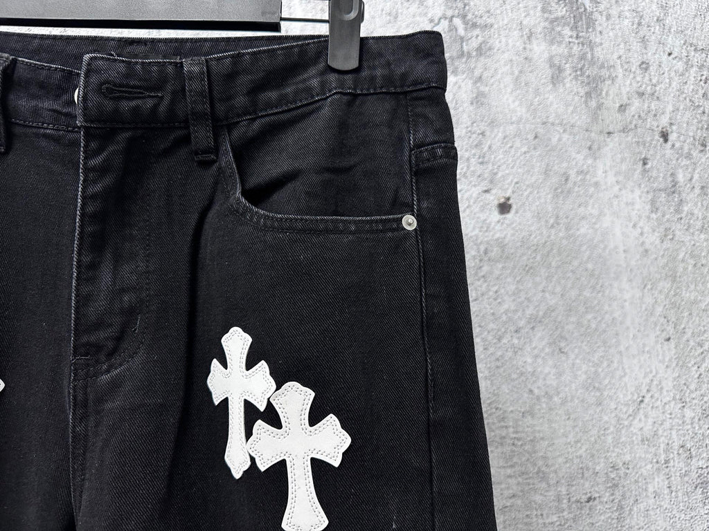 Dark denim pants with large white cross patch on front pocket area