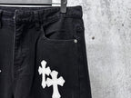 Dark denim pants with large white cross patch on front pocket area