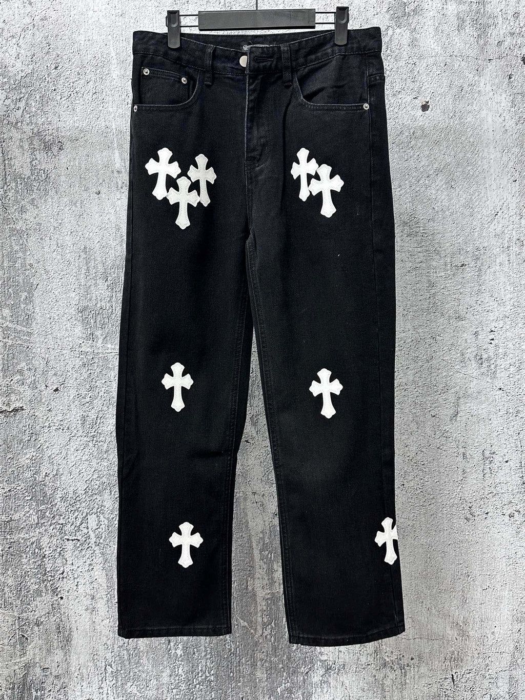 Chrome pants in dark denim with white cross and clover-style patches, front view